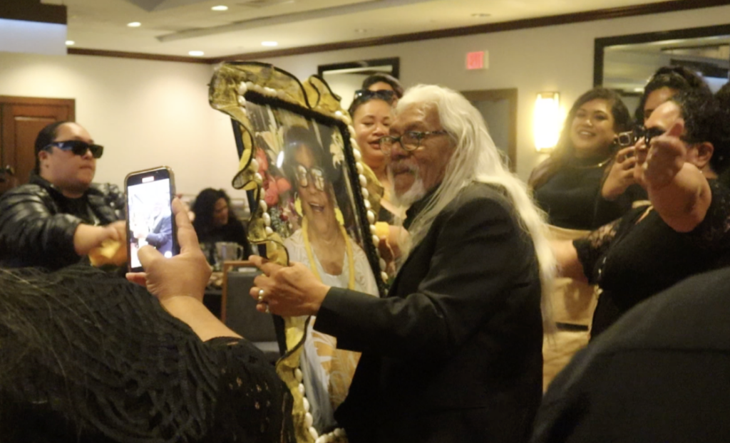 Papa Senita dances with a picture of Mama Dee at the funeral reception.